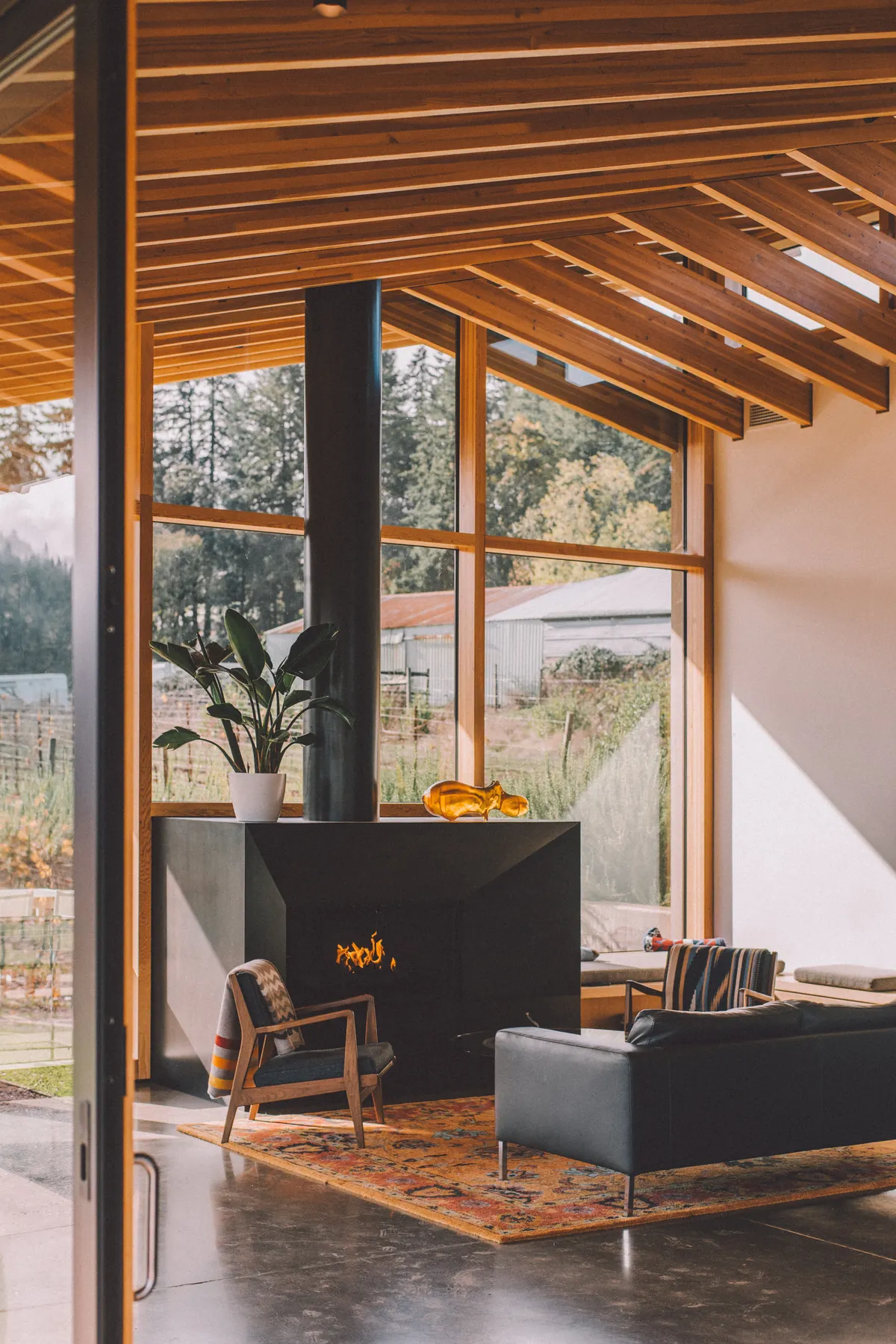 Heller Wohnraum mit großen Fenstern, Holzbalken und Kamin